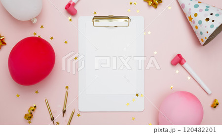 Concept of festive birthday celebrations. Blank card surrounded by colorful balloons, party hats, candles, confetti 120482201