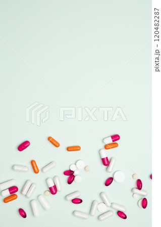 Various colorful pills and capsules scattered on a light blue background. Concept of medicine, healthcare, and pharmaceutical industry Various colorful pills and capsules scattered on a light blue background. Concept of medicine, healthcare, and pharmaceutical industry 120482287