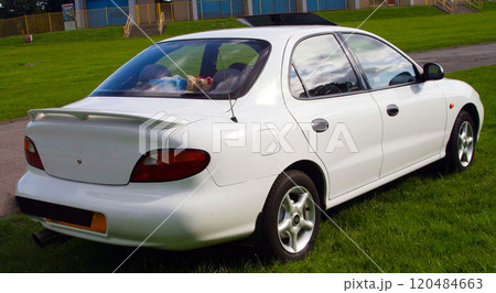 sleek classic white sedan parked on a grassy field, showcasing its elegant design and functionality in an outdoor environment 120484663