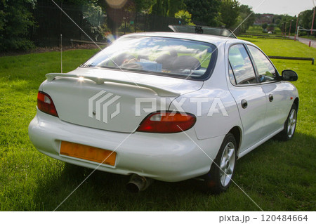 sleek classic white sedan parked on a grassy field, showcasing its elegant design and functionality in an outdoor environment sleek classic white sedan parked on a grassy field, showcasing its elegant design and functionality in an outdoor environment 120484664