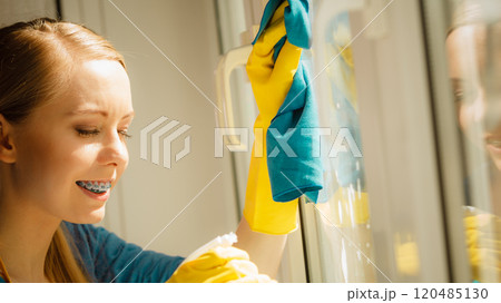 Girl cleaning window at home using detergent rag 120485130