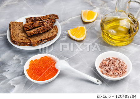 Red salmon caviar, rye bread and cooking oil on the kitchen table. Red salmon caviar, rye bread and cooking oil on the kitchen table. 120485284