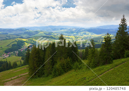 beautiful view of a countryside in carpathian mountains. remote district. cloudy weather in summer. trees on the steep slope. village in the valley. dappled light. green environment 120485748