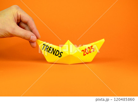 Planning trends 2025 new year symbol. Concept words Trends 2025 on beautiful yellow paper boat. Beautiful orange paper background. Businessmen hand. Business trends 2025 new year concept. Copy space. Planning trends 2025 new year symbol. Concept words Trends 2025 on beautiful yellow paper boat. Beautiful orange paper background. Businessmen hand. Business trends 2025 new year concept. Copy space. 120485860