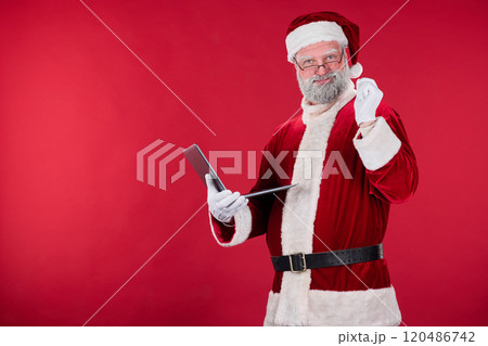 Holding Tablet Santa Claus in Red Suit Smiling 120486742