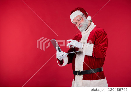 Reading From Digital Device by Santa Claus in Red Suit 120486743