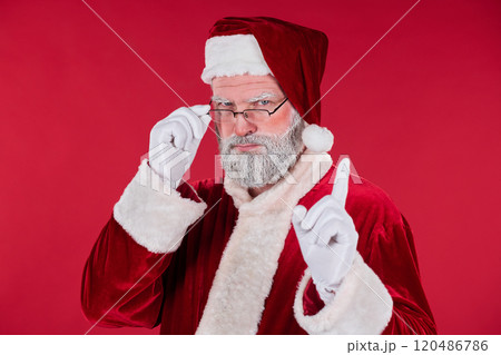 Portrait of Senior Santa Claus Adjusting Glasses on Red Background 120486786