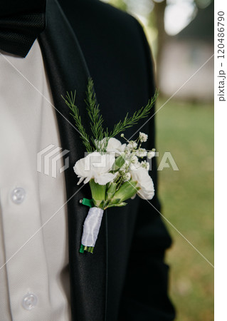 A man in a tuxedo has a white flower boutonniere on his jacket A man in a tuxedo has a white flower boutonniere on his jacket 120486790
