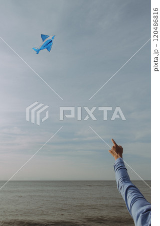 A person excitedly points at a blue paper airplane in the sky A person excitedly points at a blue paper airplane in the sky 120486816