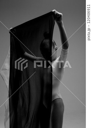 A striking black and white photograph depicting a woman holding a black cloth A striking black and white photograph depicting a woman holding a black cloth 120486911