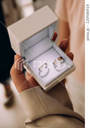 A person is holding a small box with two wedding rings inside A person is holding a small box with two wedding rings inside 120486919