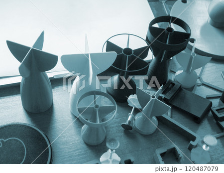 Prototype model of rocket bomb tip printed on 3D printer. Small models of tail fins, tail cone printed on 3D printer from molten plastic on table. New modern innovation printing technology Prototype model of rocket bomb tip printed on 3D printer. Small models of tail fins, tail cone printed on 3D printer from molten plastic on table. New modern innovation printing technology 120487079