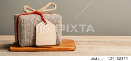 Wrapped gift box with tag on wooden board, soft background, minimalist style. Wrapped gift box with tag on wooden board, soft background, minimalist style. 120488579