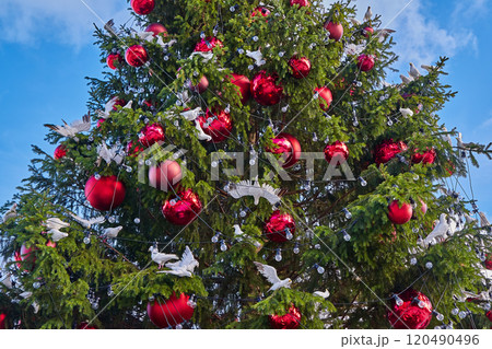 Festive Christmas tree adorned with Christmas baubles, white dove figurines, and sparkling lights 120490496