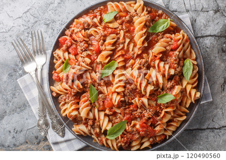 Spicy fusilli pasta with meat bolognese sauce close-up in a plate. Horizontal top view 120490560