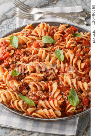 Fusilloni bolognese pasta with a hearty meat tomato sauce closeup on the plate. Vertical 120490569