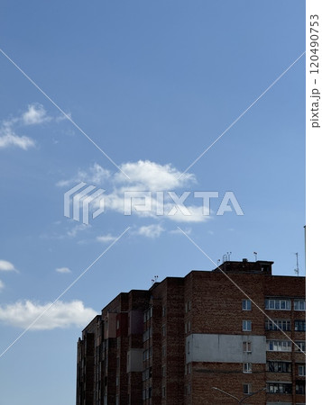 Brick Apartment Building Against a Bright Blue Sky 120490753
