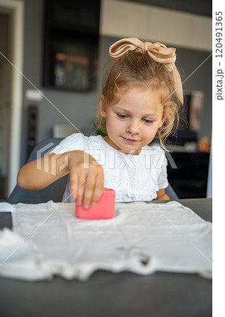 Little girl with a stamp with a name for signing children's things. Identification of personal clothing.  120491365