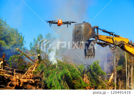 Inspector uses drone to monitor burning of trees as part of land clearing process. 120491419