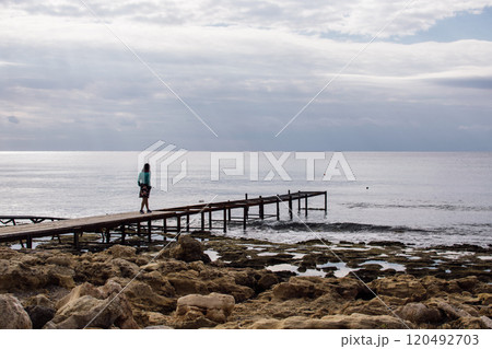 a young woman in bright clothes on an old rusty pier on the seashore, Ayia Napa, Cyprus 120492703