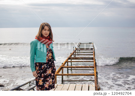 a young woman in bright clothes on an old rusty pier on the seashore, Ayia Napa, Cyprus 120492704