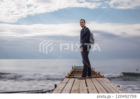 young man with a backpack on the seashore young man with a backpack on the seashore 120492709