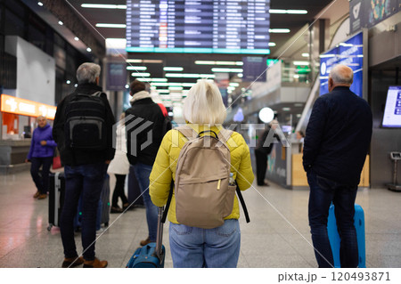 Traveler tourist happy smiling joyful fun mature elderly senior lady woman 55 years old with hand luggage, backpack holds passport and waits for flight travel at international airport terminal. Traveler tourist happy smiling joyful fun mature elderly senior lady woman 55 years old with hand luggage, backpack holds passport and waits for flight travel at international airport terminal. 120493871