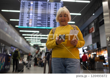 Traveler tourist happy smiling joyful fun mature elderly senior lady woman 55 years old with hand luggage, backpack holds passport and waits for flight travel at international airport terminal. Traveler tourist happy smiling joyful fun mature elderly senior lady woman 55 years old with hand luggage, backpack holds passport and waits for flight travel at international airport terminal. 120493872
