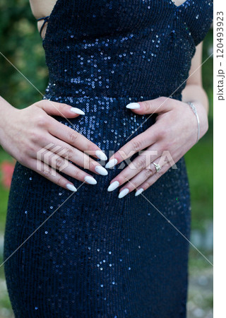 Young woman wearing a formal dark blue dress and her hands with a manicure - detail Young woman wearing a formal dark blue dress and her hands with a manicure - detail 120493923