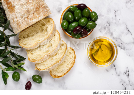 appetizer, sliced ciabatta bread, with olive oil, green olives, Chalkidiki olives, classic Green green olive, on a marble table, top view, no people, 120494232