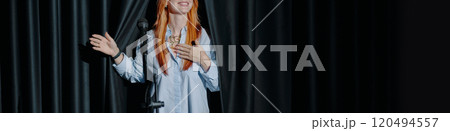 Smiling Woman Standing Next To Black Curtain Holding Mic 120494557
