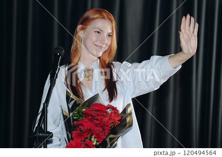 Waving Girl Holding Bouquet of Red Flowers on Stage 120494564