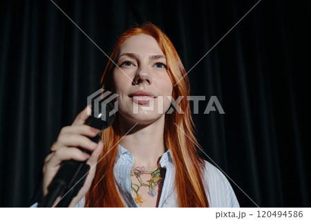 Portrait of Woman Holding Microphone on Stage Looking Forward 120494586