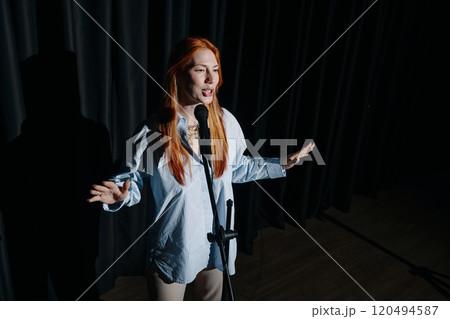 Performing on Stage with Microphone Under Spotlight 120494587