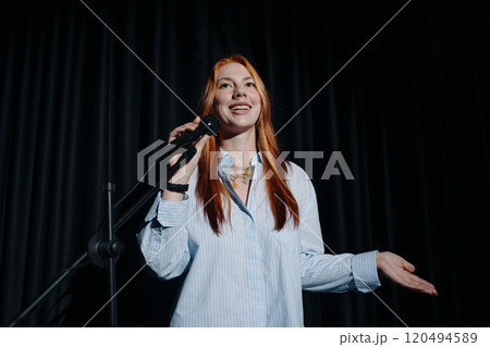 Portrait of Woman Holding Microphone on Stage Smiling 120494589
