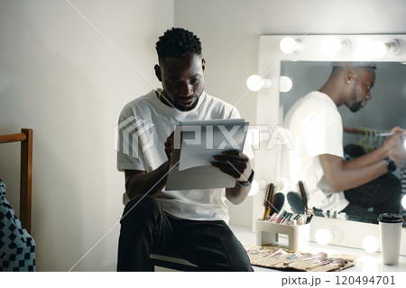 African American Man Reading Document in Dressing Room 120494701