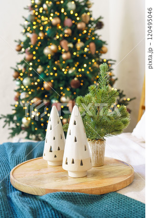 Holiday display with ceramic trees and a small evergreen by decorated Christmas tree background 120495046