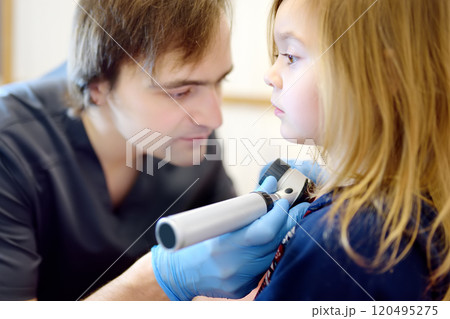 A caring doctor checks moles on the skin of a small child. A dermatologist looks at a rash on the chest of a girl using a dermatoscope. A caring doctor checks moles on the skin of a small child. A dermatologist looks at a rash on the chest of a girl using a dermatoscope. 120495275