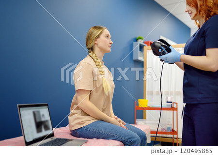 Woman with vertigo symptoms is on appointment of neurologist. Doctor making positional testing of patient with using VNG for performing Epley maneuver 120495885