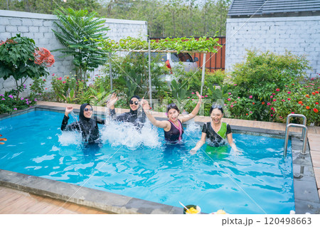 A group of joyful women are happily splashing in a beautiful pool at a tropical oasis 120498663