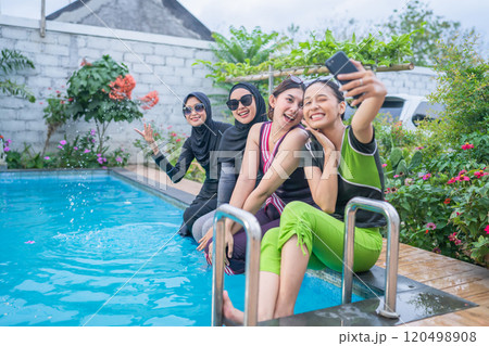 Having a fun poolside selfie with friends while wearing vibrant and colorful swimwear 120498908