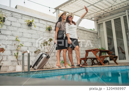 Friends Enjoying a Relaxing Time by the Poolside with Luggage and a Smartphone Friends Enjoying a Relaxing Time by the Poolside with Luggage and a Smartphone 120498997