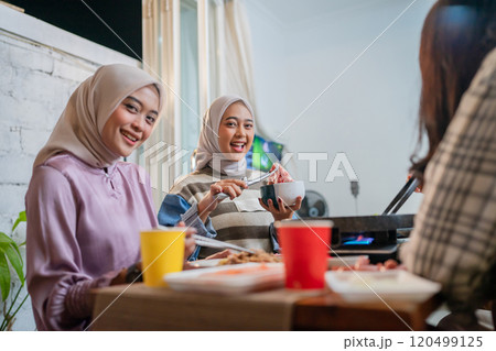 Friends enjoying a cozy meal together in a warm, modern dining setting Friends enjoying a cozy meal together in a warm, modern dining setting 120499125