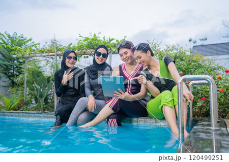 Friends enjoy leisure by the poolside, using digital devices for fun and socializing Friends enjoy leisure by the poolside, using digital devices for fun and socializing 120499251