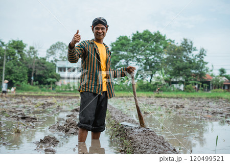 A Young Farmer Joyfully Celebrating His Success in a Waterlogged Rice Field A Young Farmer Joyfully Celebrating His Success in a Waterlogged Rice Field 120499521