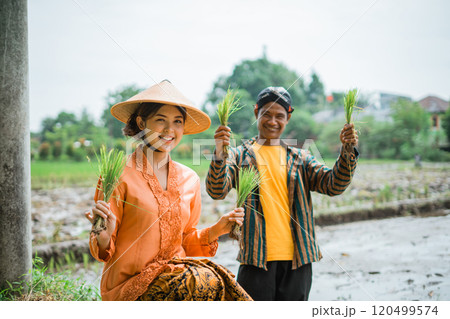 Joyful Farmers Engaged in Planting Rice Amidst a Beautiful Lush Green Field 120499574