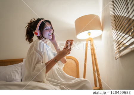 A Joyful Young Woman Enjoys Listening to Music in a Cozy Bedroom During Nighttime A Joyful Young Woman Enjoys Listening to Music in a Cozy Bedroom During Nighttime 120499688