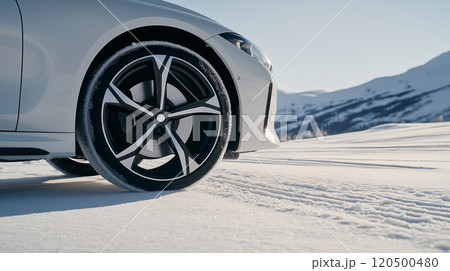 Luxury car wheel on snowy mountain road in winter sunlight 120500480