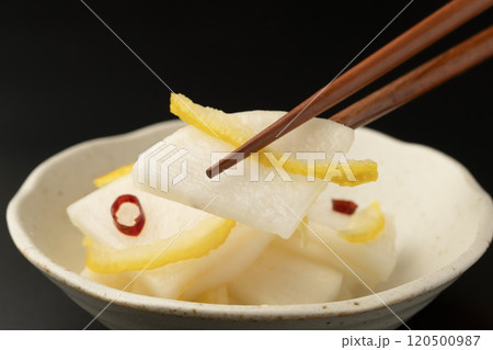 柚子大根　大根を柚子と甘酢で漬けた漬物を箸で持ち上げる 120500987