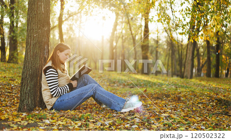 Woman reading book in autumn park Woman reading book in autumn park 120502322